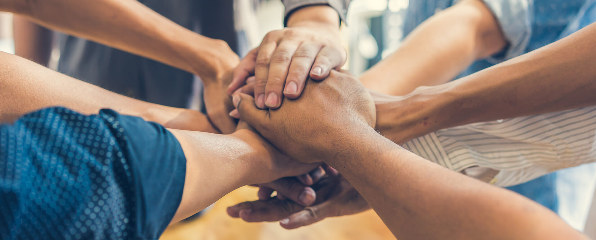 group of people stacking their hands together in the middle of their group